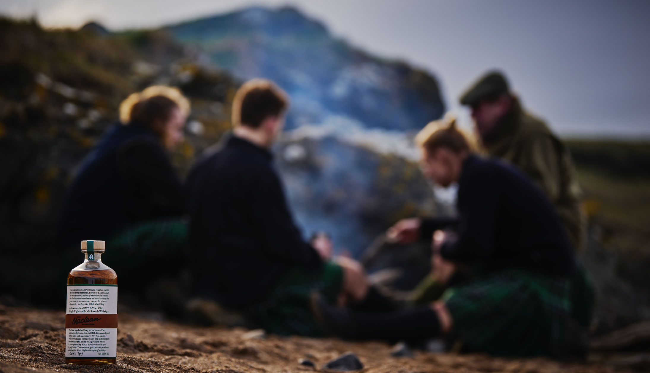 A bottle of whisky in the foreground with people sitting in the background